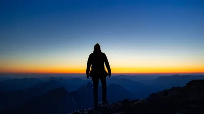 Silhouette of a hiker observing a breathtaking sunrise over the Austrian Alps.
