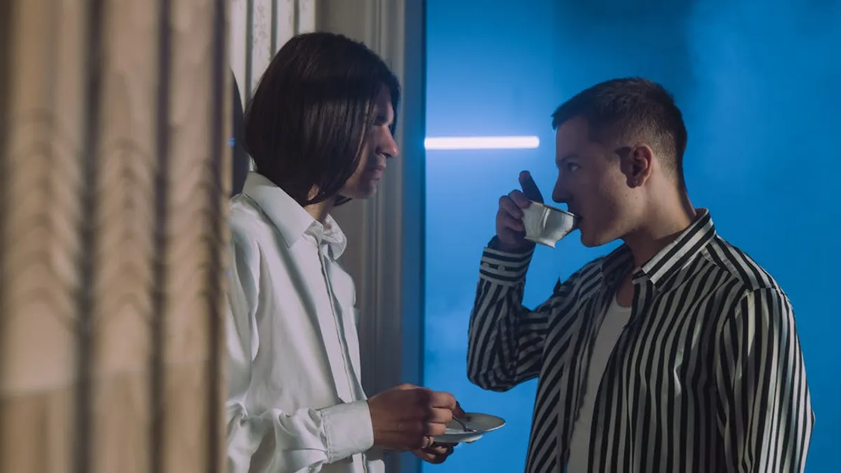 Two men engaging in conversation while enjoying tea in an indoor setting.
