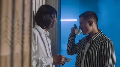 Two men engaging in conversation while enjoying tea in an indoor setting.