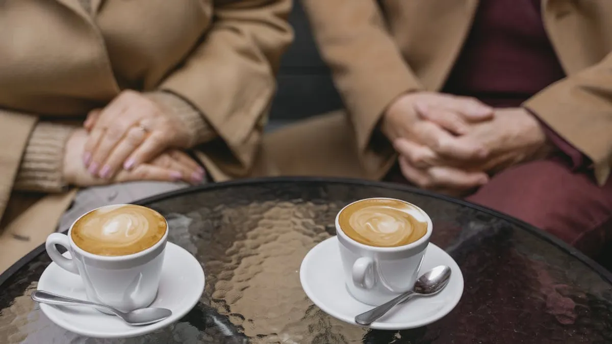 Intimate café scene featuring two lattes beautifully presented on a glass table.