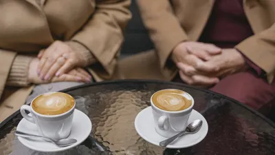 Intimate café scene featuring two lattes beautifully presented on a glass table.