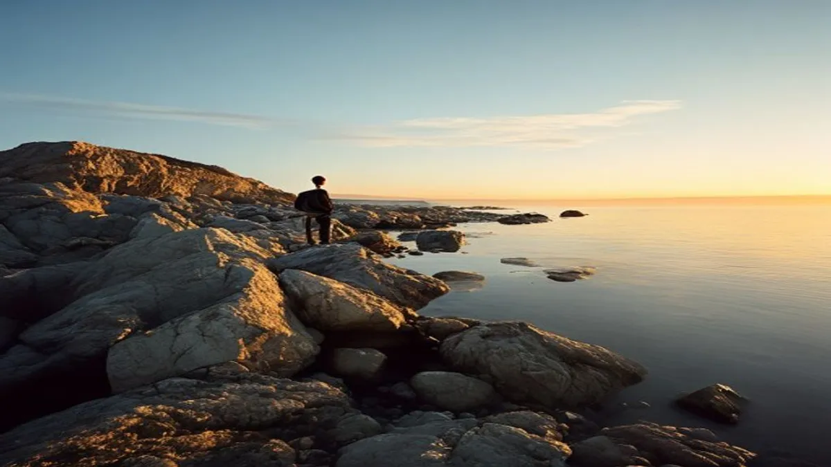 Reflective figure on rocky shoreline.