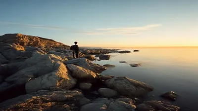 Reflective figure on rocky shoreline.