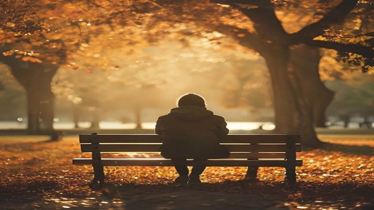 Person sitting on park bench in autumn light.