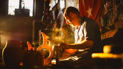 Turkish potter shaping clay in a sunlit workshop, creating beautiful pottery.