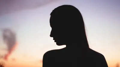 A serene silhouette of a woman against a vibrant sunset sky, capturing the tranquility of nature.
