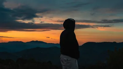 Silhouetted figure in a hoodie watches the sunrise over mountains in Oaxaca, Mexico.