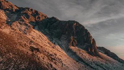 Breathtaking view of a snow-dusted mountain illuminated by a dramatic sunset sky.