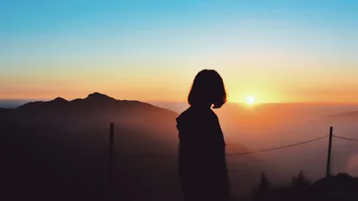 A peaceful silhouette of a woman watching the sunrise over the hills in Nainital, India.